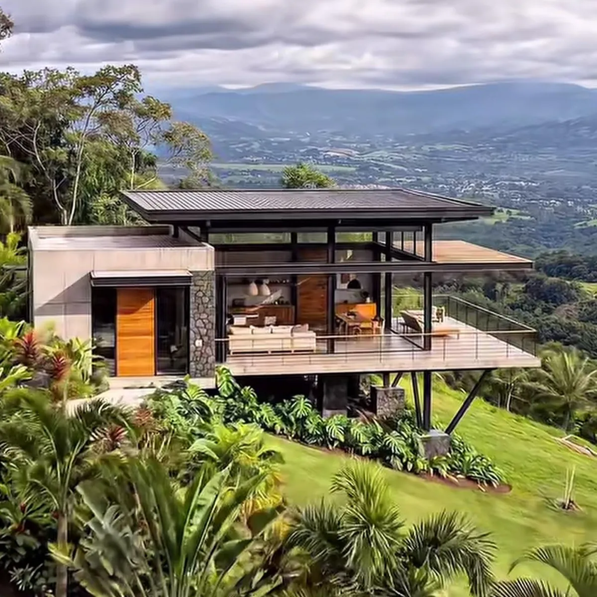 Glass-walled villa with a cantilevered deck above a green valley